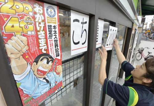 「こち亀」のコミックス第２００巻発売のポスターを張る売店の店員