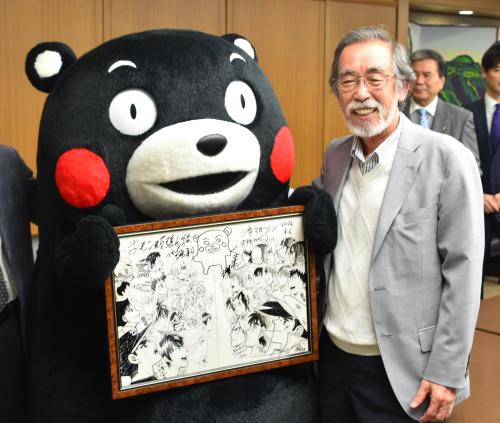 熊本地震の復興を支援するために漫画家らが描いたイラストを寄贈し、くまモンと写真に納まる川崎のぼる氏