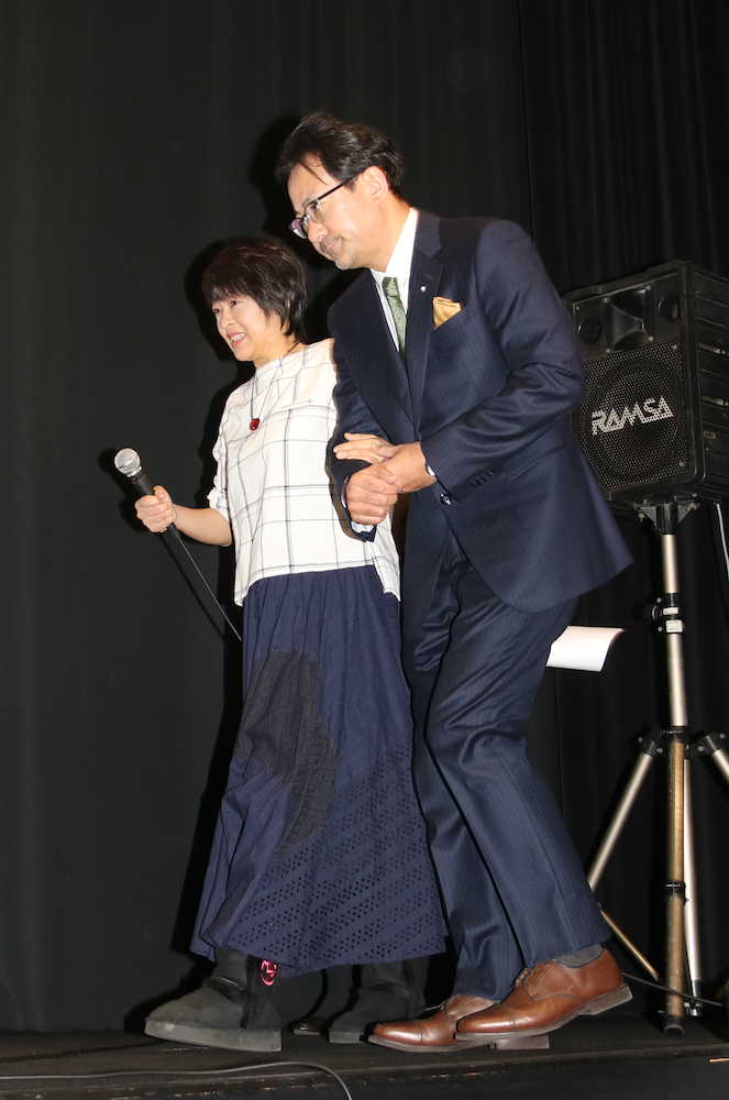 映画「ママ、ごはんまだ？」の初日舞台あいさつに白羽弥仁監督（右）と腕を組み、支えられて登壇した河合美智子