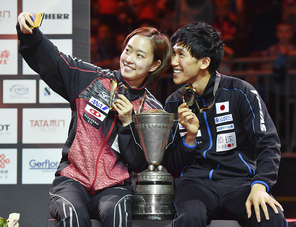 卓球の世界選手権個人戦の混合ダブルスで優勝し、メダルを手に写真を撮る吉村真晴（右）と石川佳純ペア