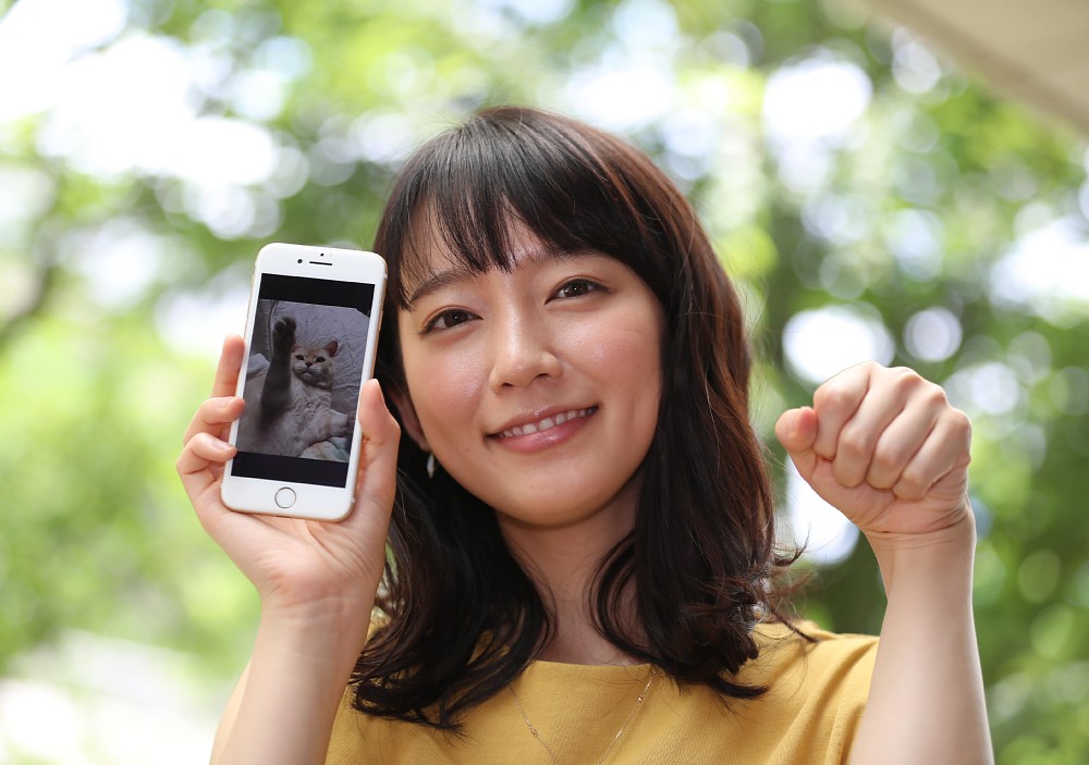 携帯電話に保存してある愛猫の写真を手に笑顔を見せる吉岡里帆