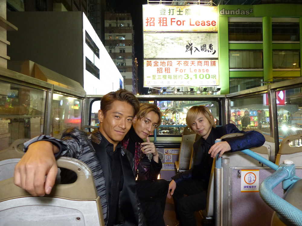 香港名物のオープントップバスで繁華街をバックに笑顔のｗ―ｉｎｄｓ．の（左から）緒方龍一、橘慶太、千葉涼平