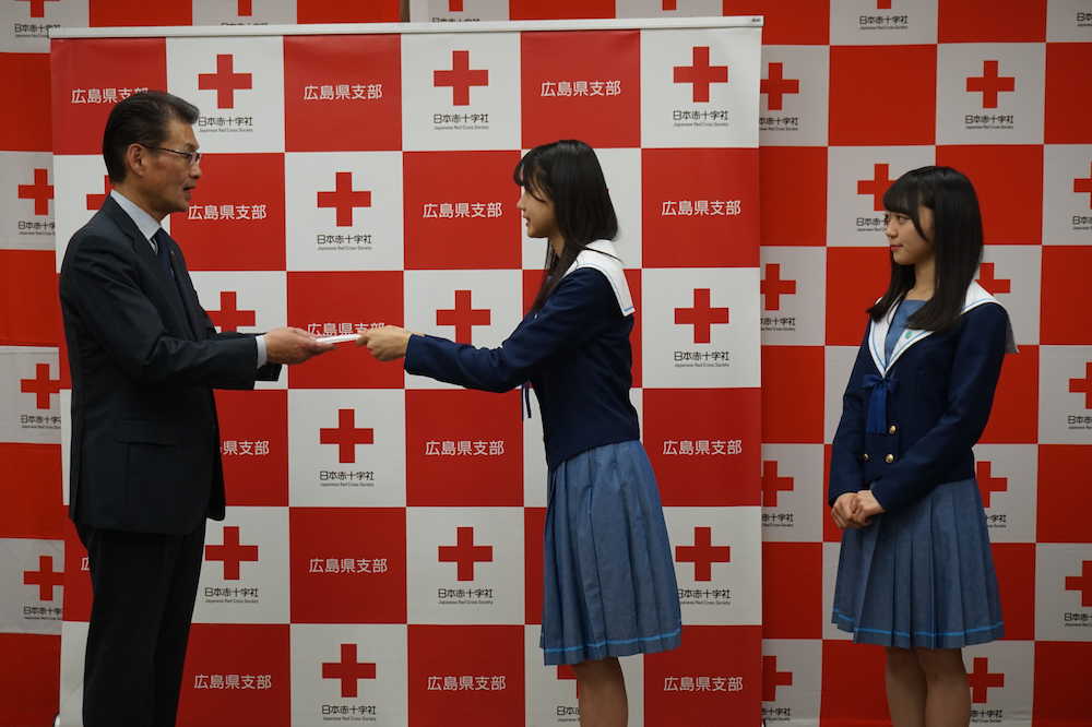 日本赤十字社広島県支部の担当者に義援金目録を手渡す
ＳＴＵの瀧野由美子（左）、土路生優里（右）　　　　　　　　　　　　　　　　　　　　　　　
