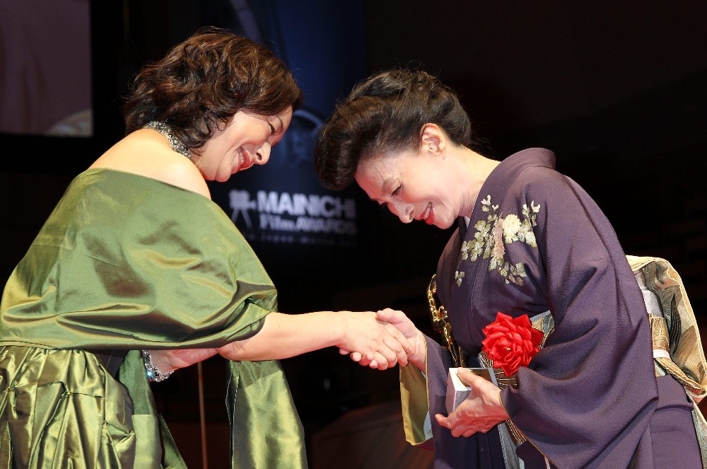 １１年２月　第６５回毎日映画コンクール表彰式で田中絹代賞を受賞し高橋惠子（左）からブロンズ像を贈られ握手を交わす
