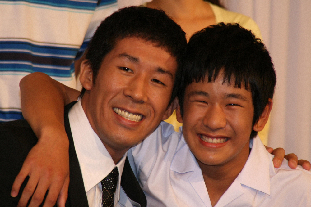 2008年、ドラマ「ホームレス中学生」の制作発表で原作者の「麒麟」の田村裕（左）と肩を組む黒木辰哉容疑者