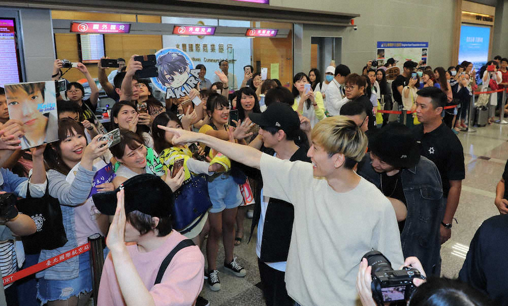 空港でファンにデビュー当時の写真を掲げられ、指をさして喜ぶw－inds.の橘慶太