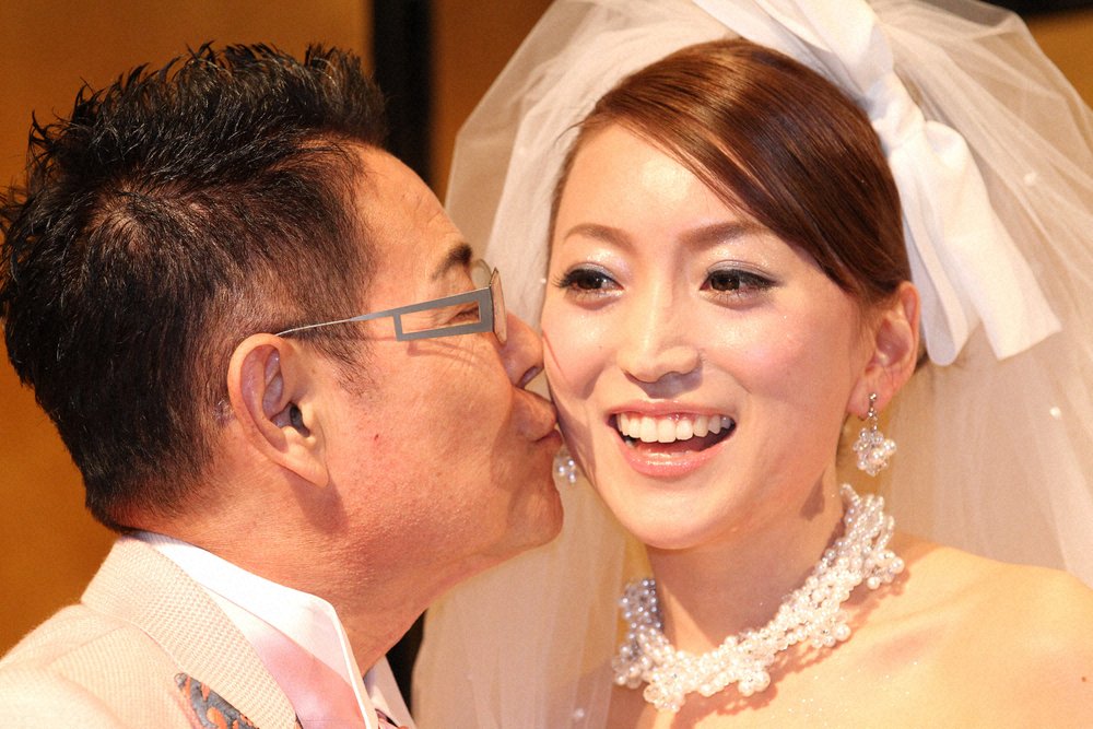 ウエディングドレス姿の綾菜夫人（右）にキスをするタレントの加藤茶