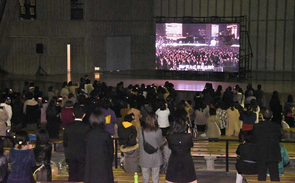 日比谷野外音楽堂に設置された大型スクリーンで国民祭典の様子を見つめる嵐のファンら