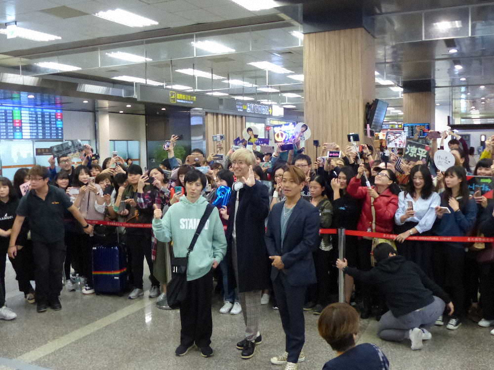 台北・松山空港で出迎えた熱烈な現地ファンをバックに撮影に応じるw－inds.の（左から）千葉涼平、橘慶太、緒方龍一