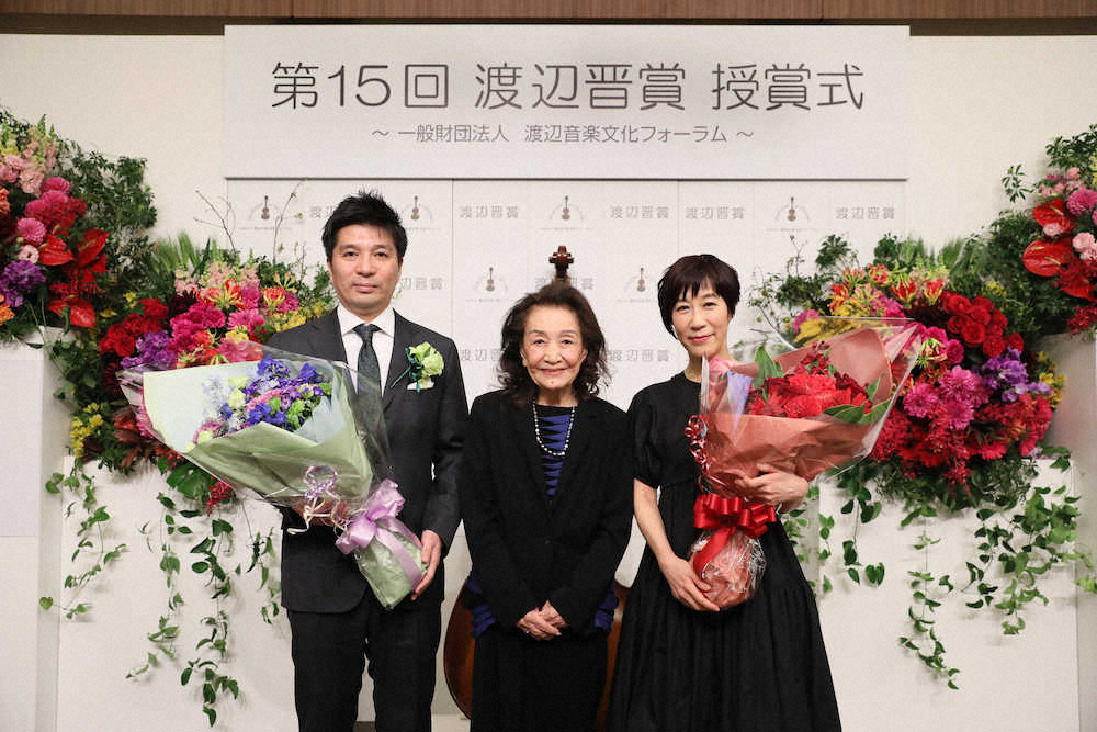 花束を手に感激する藤田晋氏と菅野よう子さん。中央は渡辺音楽文化フォーラムの渡辺美佐理事長