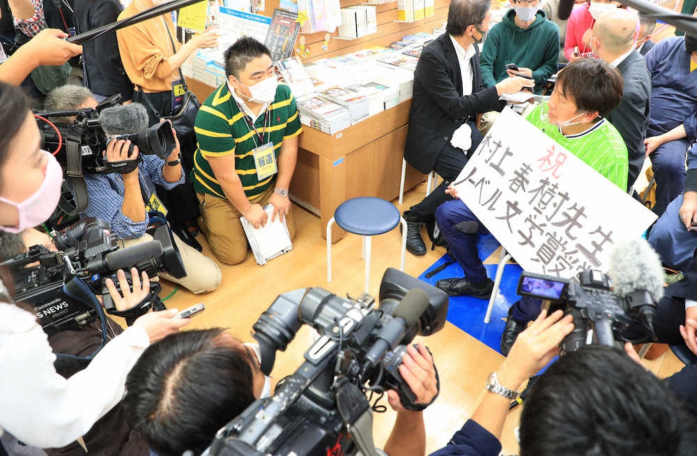 ノーベル文学賞発表後、肩を落としながら報道陣に話する村上春樹氏のファン（右）