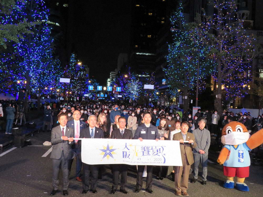 大阪市内を走るメインストリート・御堂筋で催されたイベント「大阪・光の饗宴2020」の開宴式典に出席した吉村洋文大阪府知事（前列左から4人目）、松井一郎大阪市長（同3人目）、Little　Glee　Monster（後列）ら