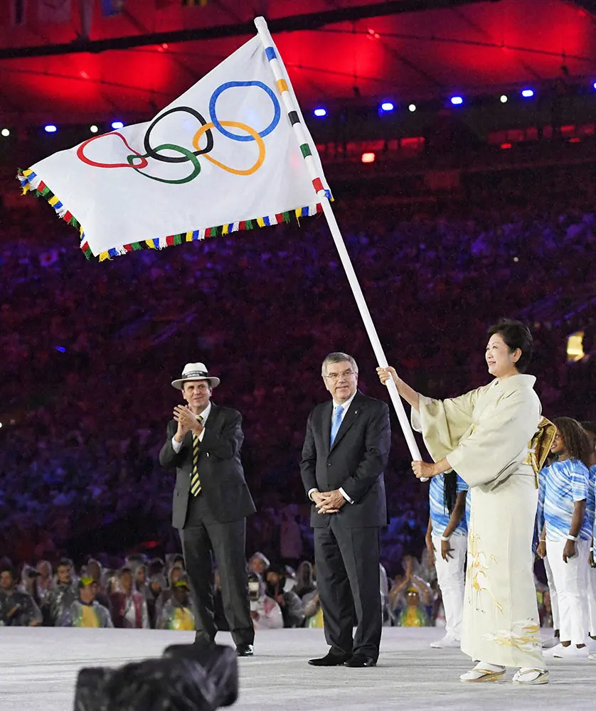 16年リオデジャネイロ五輪閉会式で、IOCのバッハ会長（中央）から引き継いだ五輪旗を持つ東京都の小池百合子知事（代表撮影）