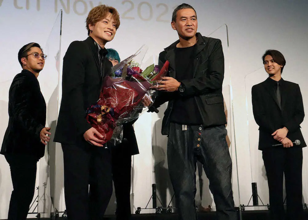 デビュー9周年を祝う花束をSABU監督（右から2人目）から贈られ笑顔の白濱