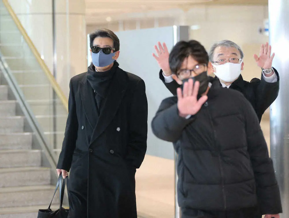 関係者にガードされながら空港到着ロビーを歩く神田正輝（左）
