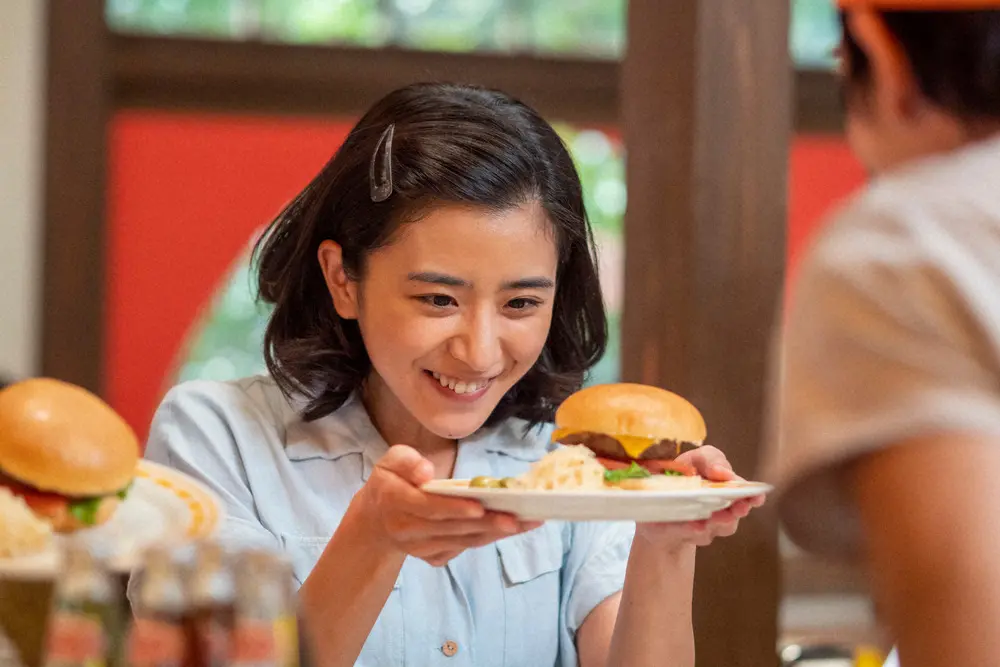 連続テレビ小説「ちむどんどん」第14話。ハンバーガーを手に目を輝かせる暢子(黒島結菜)（C）NHK