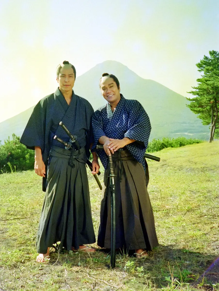 89年、開聞岳をバックに鹿賀丈史と写真に納まる西田敏行（右）