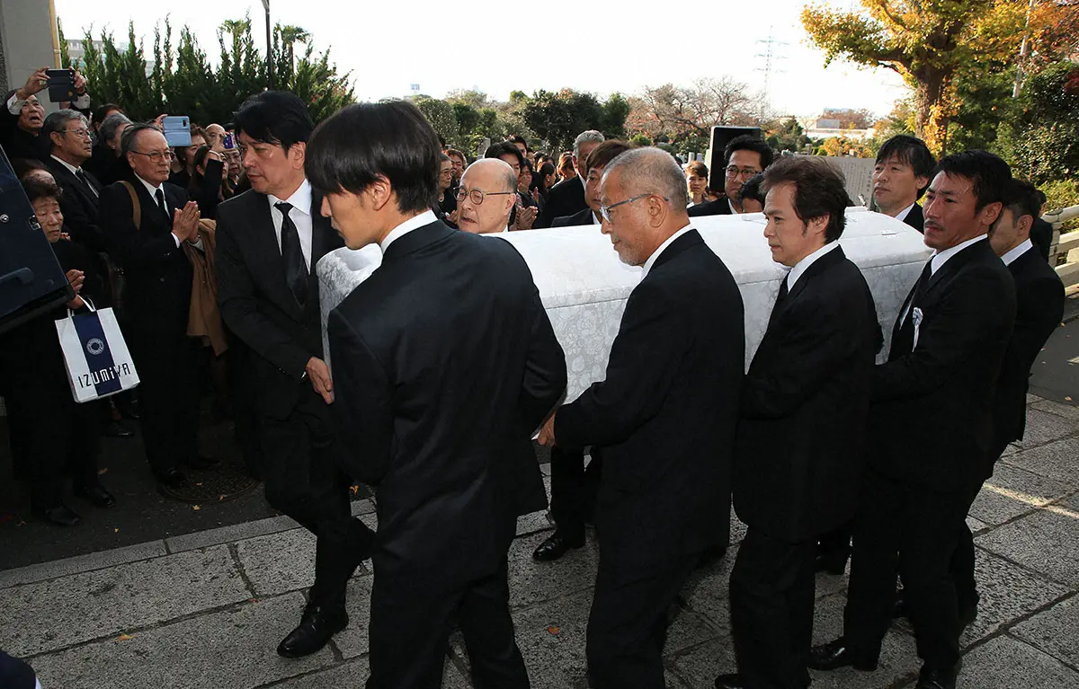 2018年12月、赤木春恵さんの葬儀・告別式で、霊きゅう車に棺を納める（左から）俳優の川崎麻世、孫の野杁俊希さん、角野卓造ら