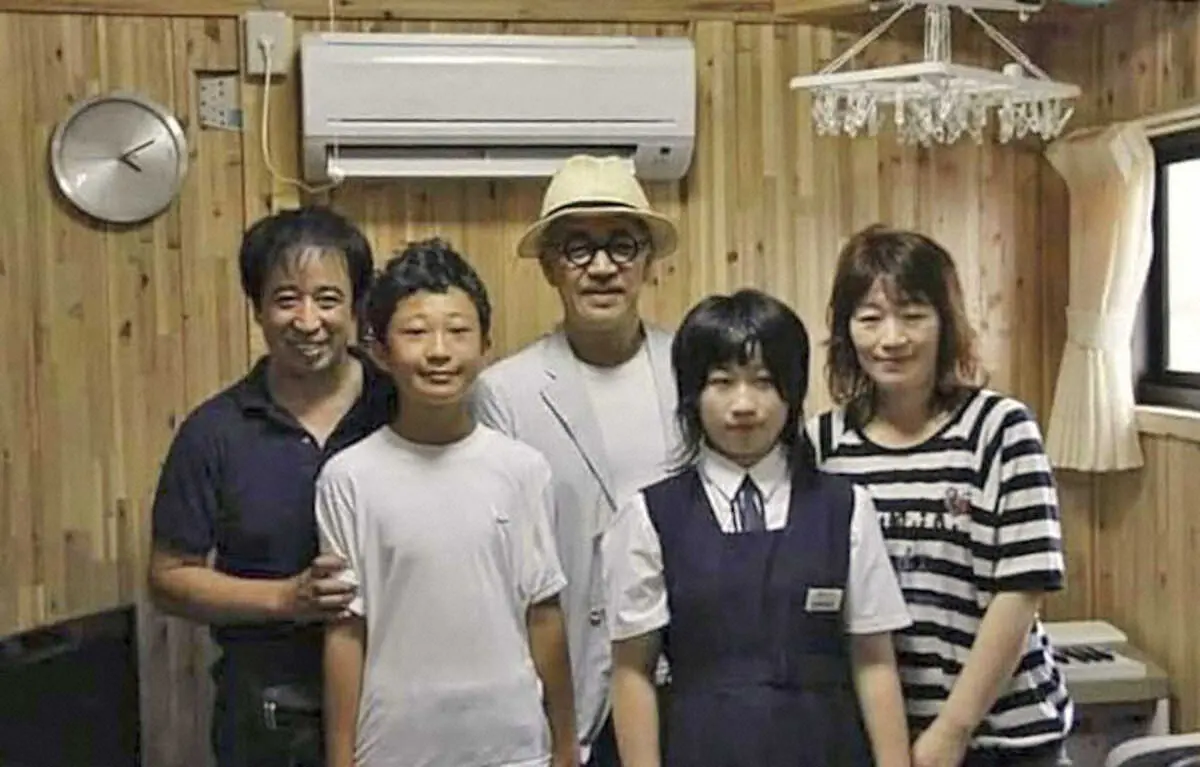 仮設住宅内で、坂本龍一さん（中央）と記念写真に納まる菅原綾乃さん（右から2人目）と家族（菅原教文さん提供）