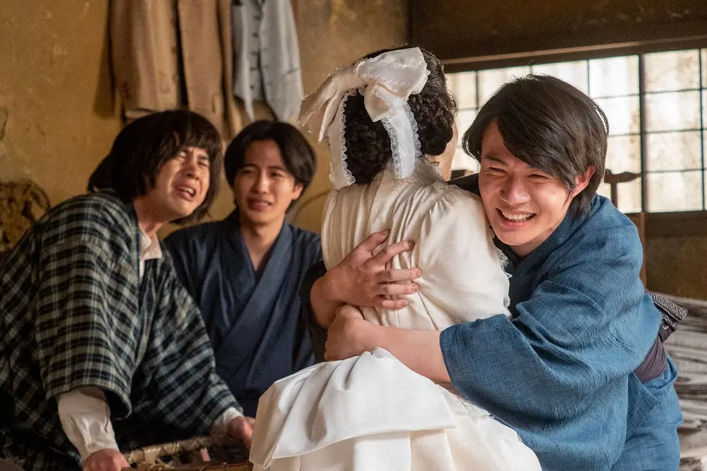 【画像・写真】連続テレビ小説「らんまん」第56話。プロポーズが成功し、寿恵子（浜辺美波）を抱き締める万太郎（神木隆之介・右端）。見守る丈之助（山脇 辰哉・左端）はこの表情（C）NHK
