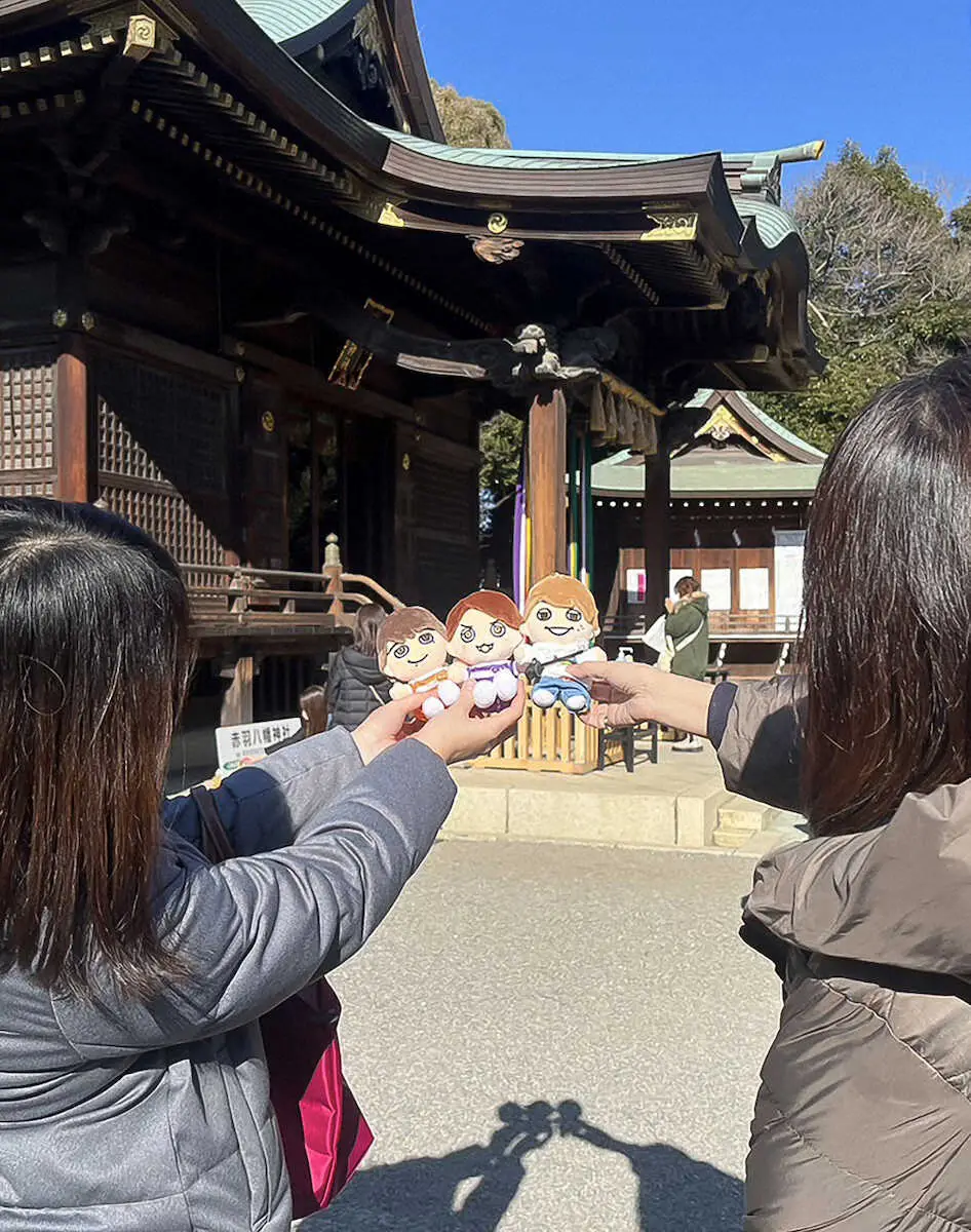 赤羽八幡神社の本殿をバックにグッズを掲げるファン（撮影・塩野　遥寿）