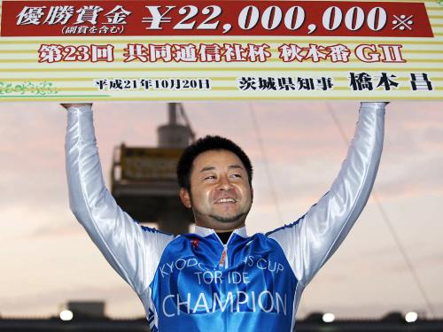優勝し、賞金ボードを掲げる山崎芳仁
