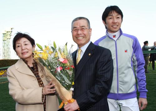定年で引退する池江郎調教師（中央）は花束を手に敏子夫人（左）と武豊騎手に囲まれ笑顔を見せる