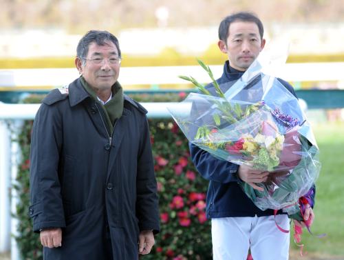 父・飯田明師（左）から花束を贈られ、記念写真に納まる飯田