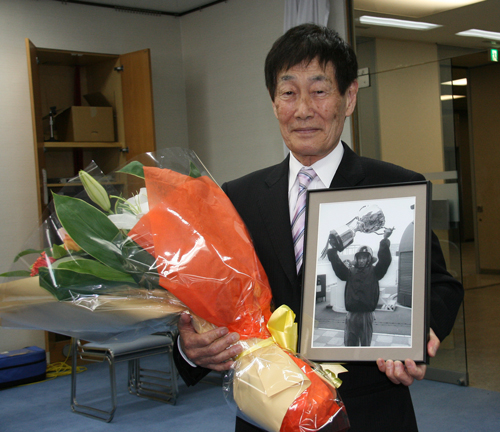 今月７日、現役最年長の７３歳で引退し、会見で花束と写真を手にする加藤峻二さん