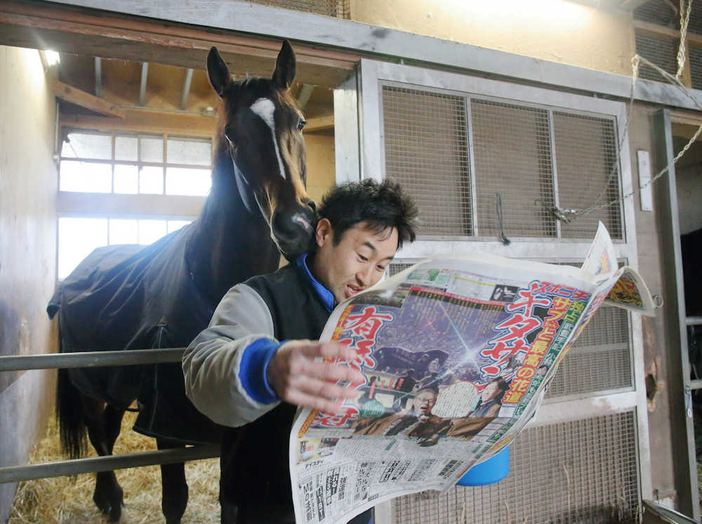 「もっと見せて〜！」とばかりに、辻田厩務員の後から有馬記念で１面を飾った本紙大阪版をのぞきこむキタサンブラック