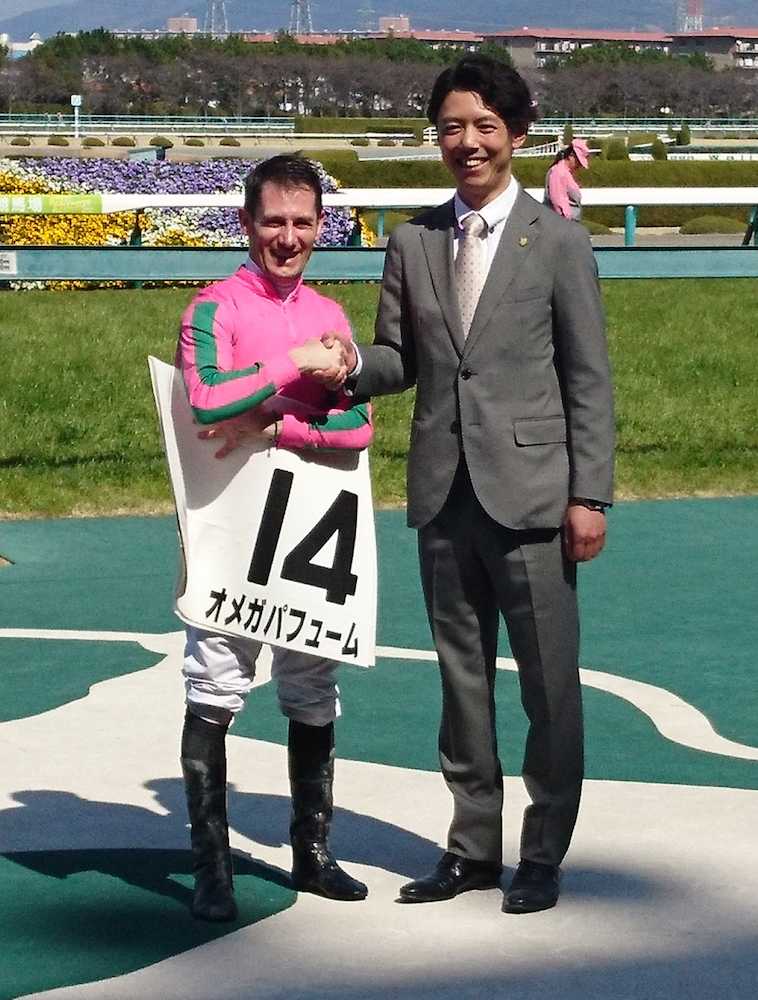 阪神６Ｒで厩舎開業初勝利を挙げガッチリ握手をかわす安田翔伍師（右）とＭ・デムーロ