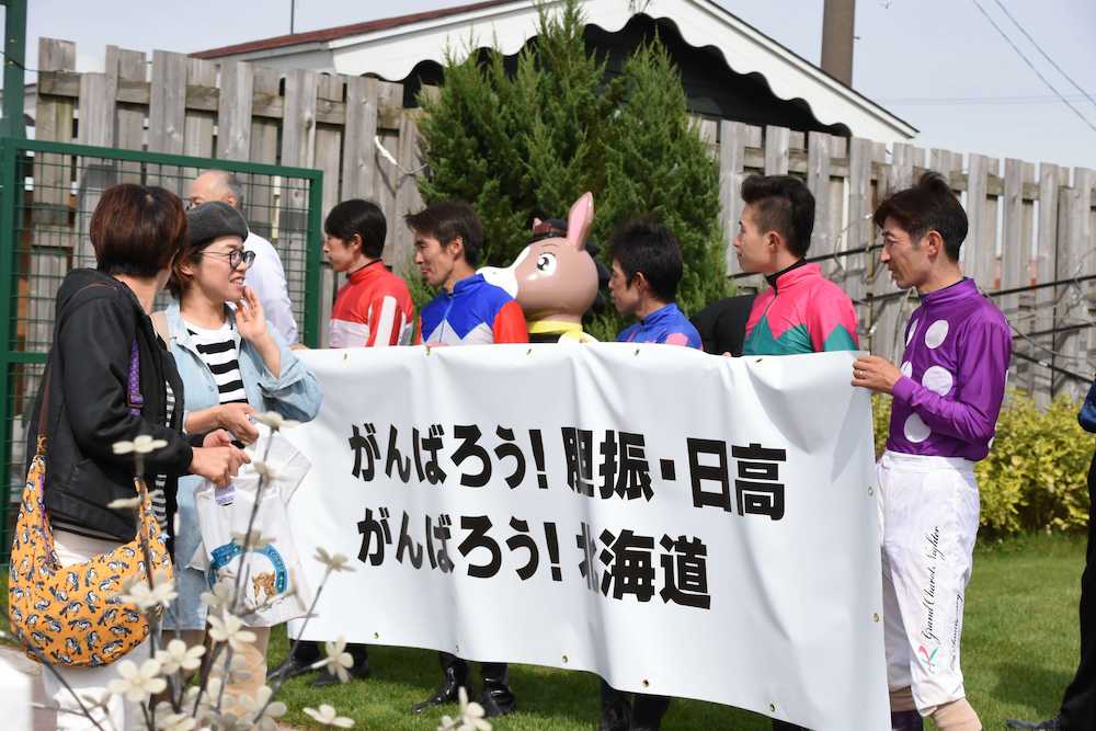 競馬場開門時、「がんばろう！胆振・日高　がんばろう！北海道」の幕を掲げて入場客を迎え入れるホッカイドウ競馬所属の騎手たち