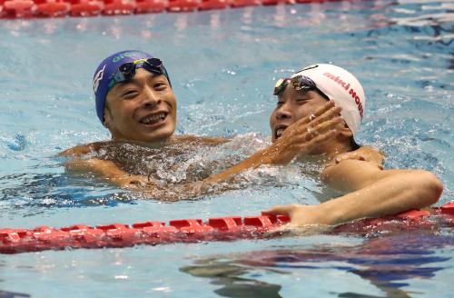 ともに１００ｍ背泳ぎでの五輪出場を決め、喜びを分かち合う入江（左）と長谷川