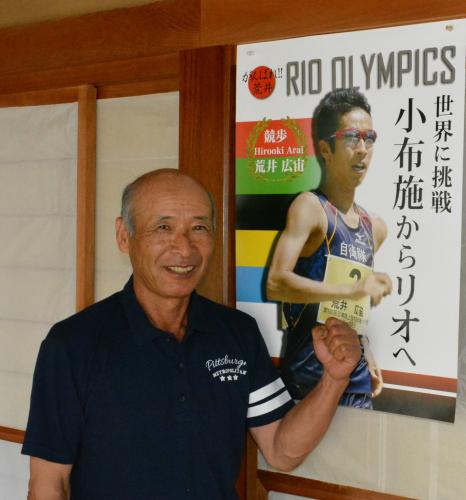 親戚の三田博幸さんが作成した、「小布施からリオへ」と書かれたポスターを前にガッツポーズで喜びを表現する父・康行さん