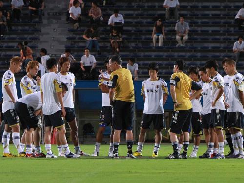＜サッカー日本代表練習＞スタンドからザッケローニ新監督（上のボックスの右から２人目）がみつめる中、原監督代行（中）の指示を聞く本田（左）らイレブン