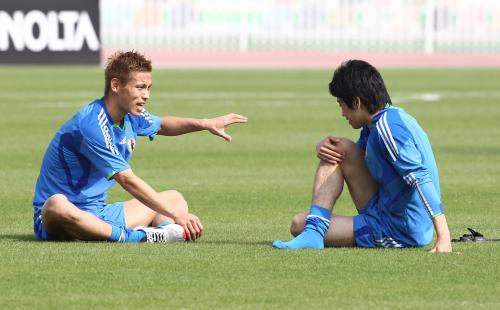 練習後、ピッチに腰を下ろして話す本田圭（左）と香川