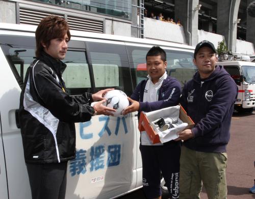 仙台の平瀬アンバサダー（左）にサッカーボールやスパイクを手渡す福岡サポーター