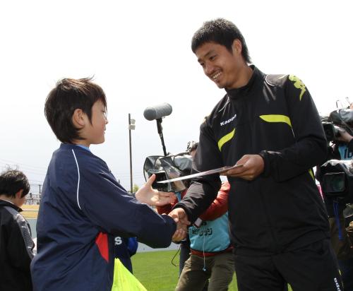 岩手県沿岸部で被災したサッカー少年に自身のサイン入り下敷きをプレゼントする小笠原