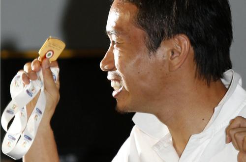 笑顔でサッカーイタリア杯優勝のメダルを報道陣に掲げるサッカー日本代表の長友佑都