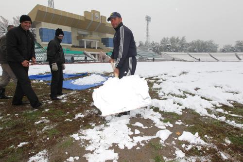 雪の下からは芝生ではなく、土が見え・・試合会場のドゥシャンベ・セントラル・スタジアムは大雪に覆われ関係者が懸命に雪かきをしていた