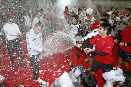 シャンパンをかけ合ってＪ１昇格を祝う札幌イレブン。左手前は石崎監督