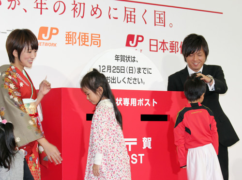 「平成２４年用年賀状　引受開始セレモニー」で子どもの頭をなでる遠藤保仁（右）左は夏菜