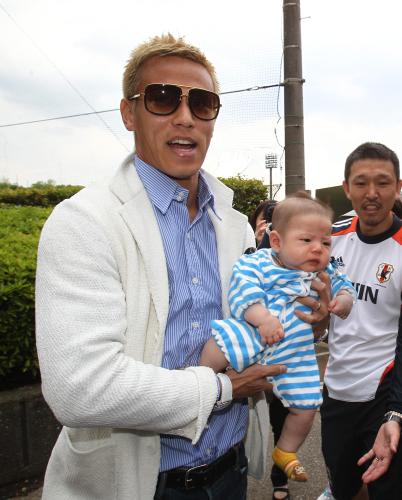 サポーターの赤ちゃんを抱いて笑顔を見せる本田
