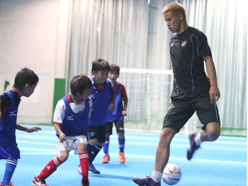 サッカー教室で子どもたちとミニゲームで汗を流す本田は、華麗なヒールパスを披露