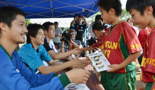 地元の子どもにサインを渡し握手する（手前左から）小笠原満男、内田篤人、吉田麻也の各選手