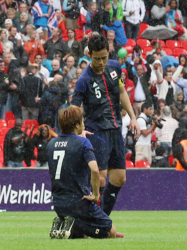 ＜日本・メキシコ＞試合終了後、降りしきる雨の中、立ち上がれない大津（左）に手を差し伸べる吉田