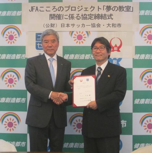 ＪＦＡこころのプロジェクト「夢の教室」協定締結式で握手を交わす日本サッカー協会の大仁会長（左）と大和市の大木市長