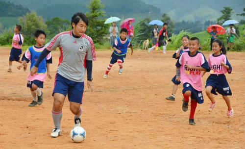20日、タイ・ウンピアムのミャンマー難民キャンプで、子どもたちとサッカーをする元Ｊリーガーの丸山良明さん