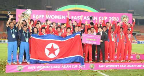 東アジア杯を優勝した北朝鮮チームが表彰台で喜ぶ