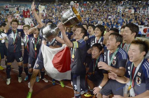 サポーターの前で東アジア杯の優勝トロフィーを掲げる駒野（中央）と大喜びの日本イレブン